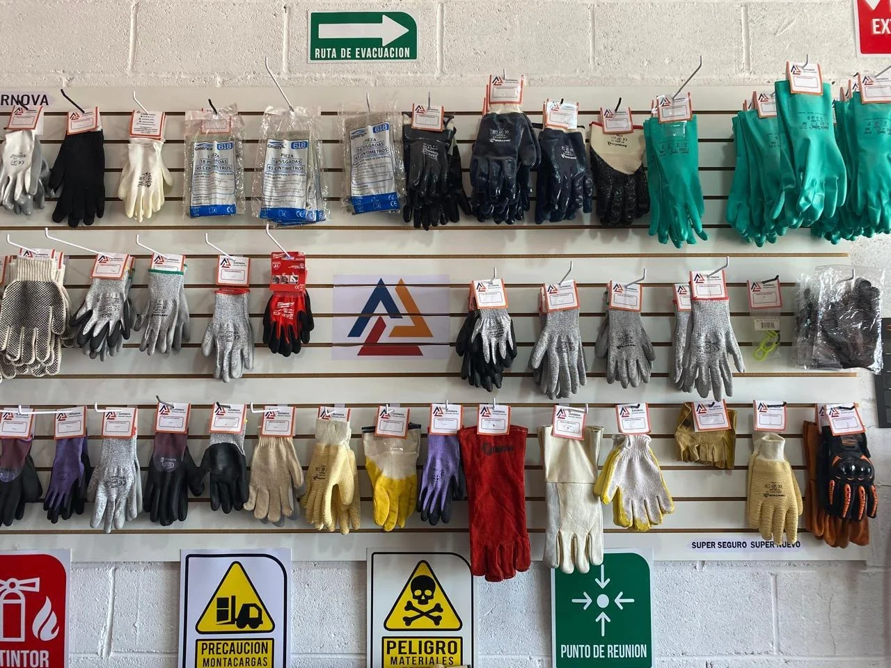 Pared de exhibición de guantes de trabajo en la tienda de Supernova, cada modelo con su etiqueta y el logo de la marca pintado al centro